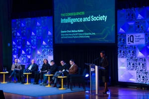 Image of a panel of presenters on a colorfully lit stage