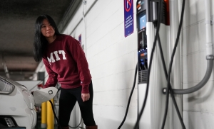 MIT student standing at an electric charging station fueling her vehicle