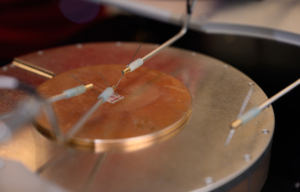 An oxide thin film sits on a probe station in a lab, where its electrical resistance is being measured.