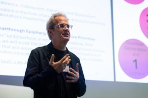 Per Urlaub makes a presentation, with a presentation screen behind him.