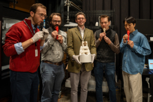 Nate Steele, Mark Rau, Jared Katz, Benjamin Sabatini, and Jin Woo Lee stand in a semicircle. Four are blowing into replica whistles, while one holds an ancient whistle in a protective cradle.