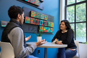 An MIT staff member meets one-on-one with a student in an Undergraduate Advising Center advising space beneath artwork reading "Empower."