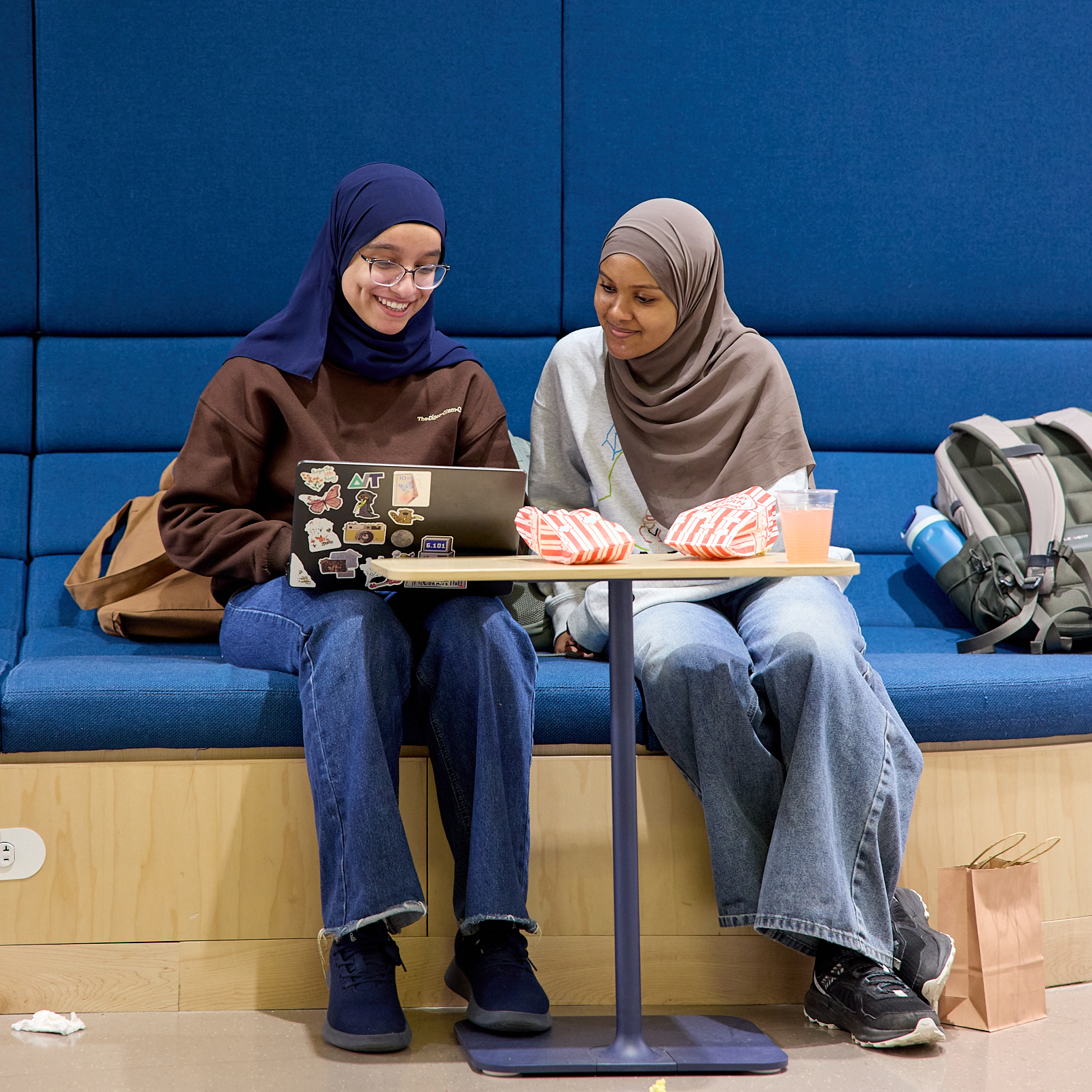 Two MIT students study together in a blue upholstered pod at the entrance to the Undergraduate Advising Center.